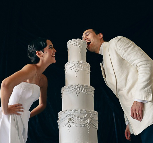 Brautpaar beißt lachend in die Hochzeitstorte